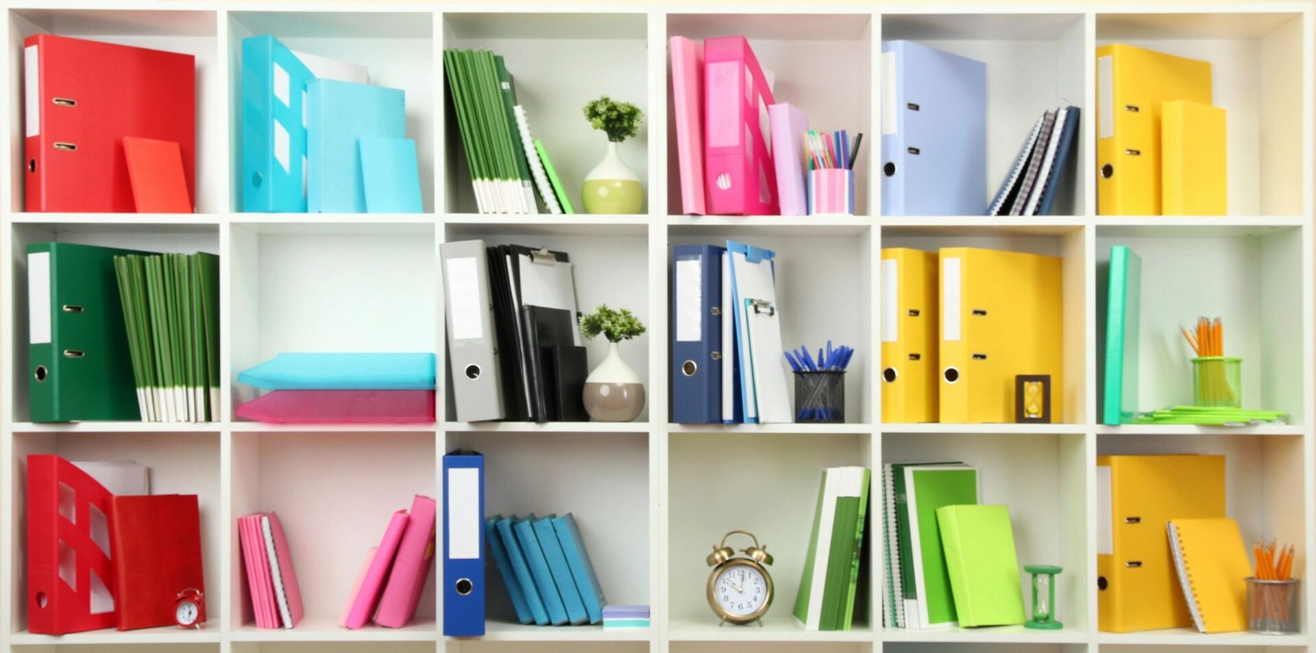 A bookshelf with many different colored books and folders.